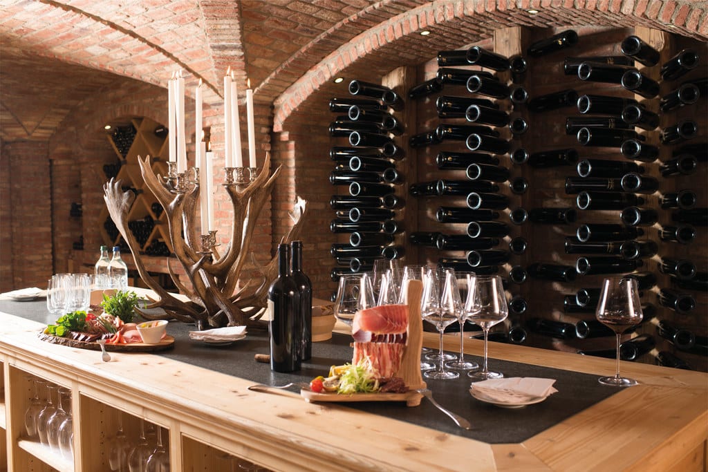 Wine cellar and table with empty glasses, bottles, candles and cold appetizer