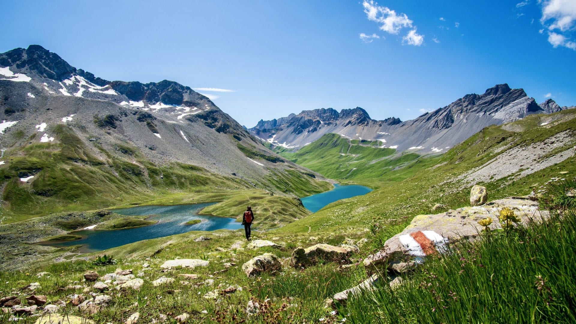 A woman wearing black in front of two lakes surrounded by Mountains in Davos