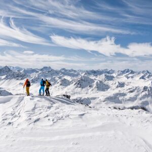 three skiers standing on top of mountain in winter in Davos