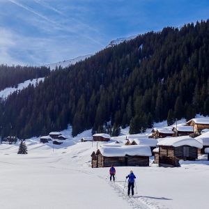 two skiers in skitour some houses of wood with snow in Monstein Village