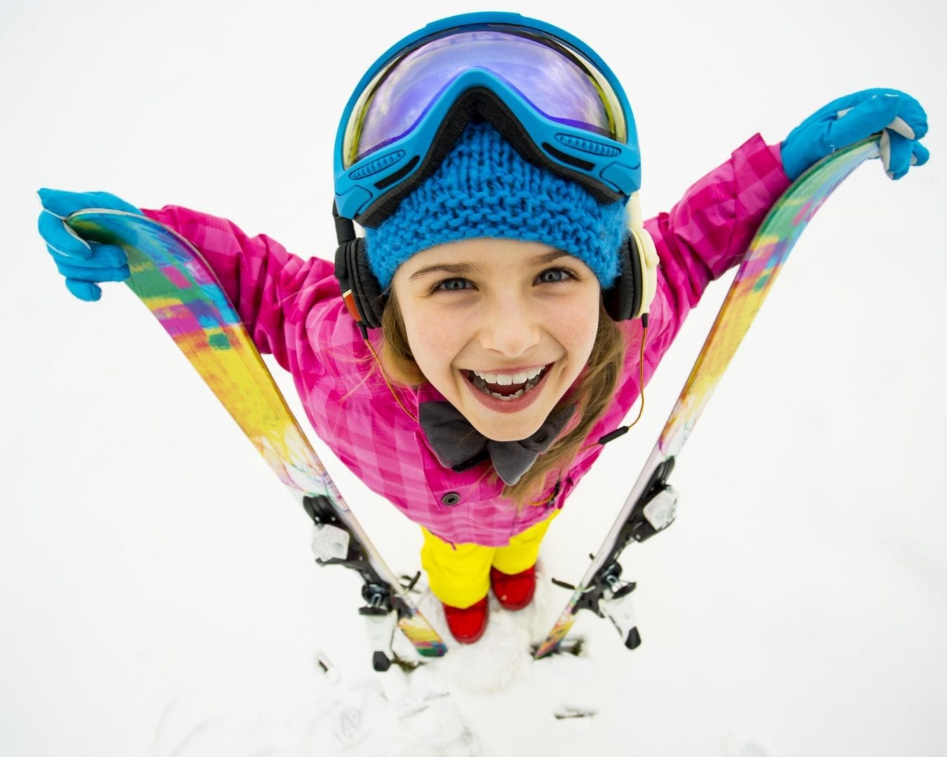 A child with all the ski equipment looking up and smiling