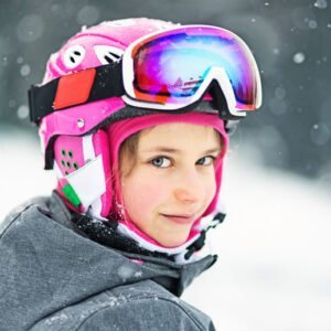 a girl wearing pink helmet looking and smiling in Klosters